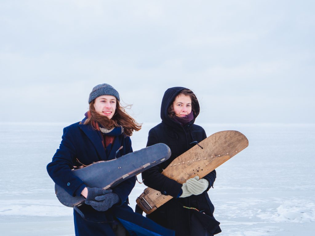 Eva Väljaots & Robbie Sherratt walking on the Baltic Sea with a kannel and fiddle case.